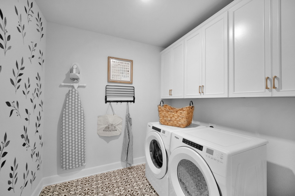 Photo of a mid-sized country single-wall dedicated laundry room in Houston with recessed-panel cabinets, white cabinets, multi-coloured walls, ceramic floors, a side-by-side washer and dryer and multi-coloured floor.