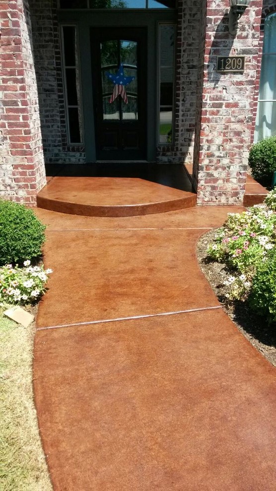This is an example of a mid-sized traditional front yard verandah in Oklahoma City with stamped concrete and a roof extension.