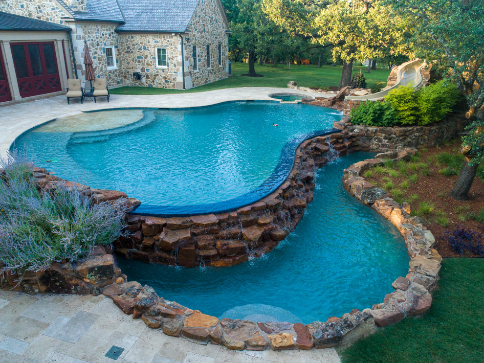 Foto de piscina con tobogán natural rústica grande a medida en patio trasero con adoquines de piedra natural
