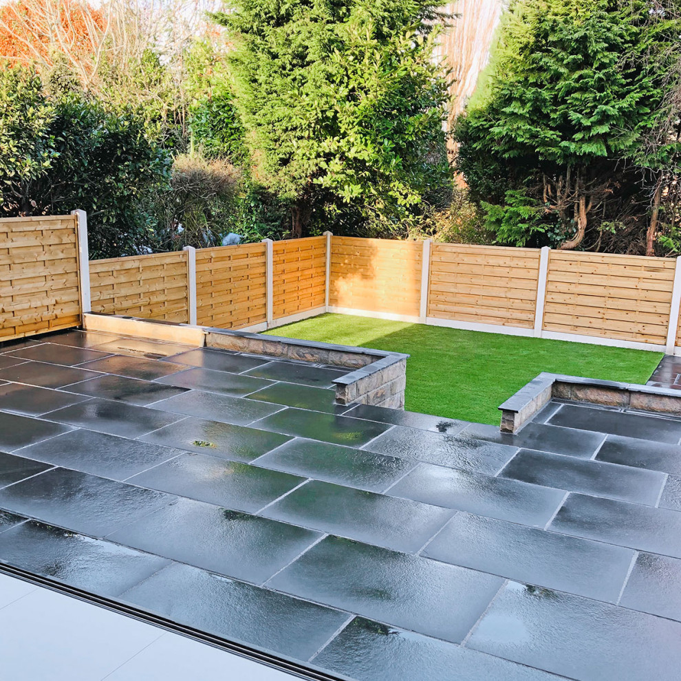 Photo of a mid-sized traditional backyard patio in Hertfordshire with natural stone pavers.