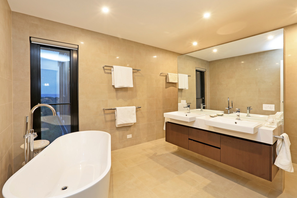 This is an example of a large contemporary master bathroom in Melbourne with furniture-like cabinets, medium wood cabinets, a freestanding tub, multi-coloured tile, stone tile and engineered quartz benchtops.