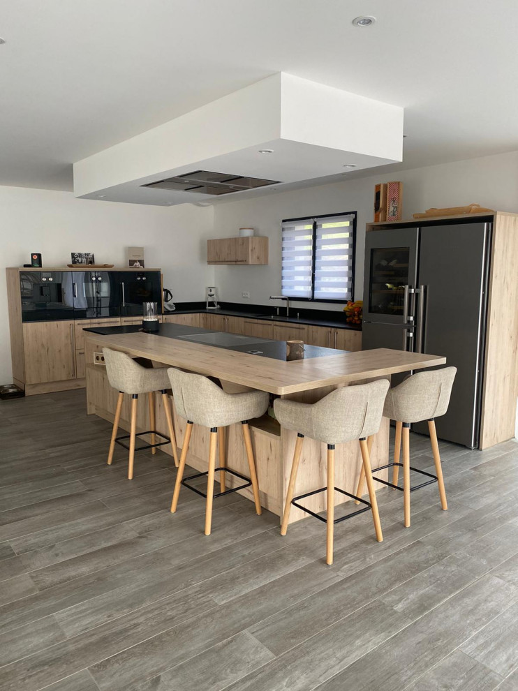 Large scandinavian l-shaped open plan kitchen in Lyon with an integrated sink, beaded inset cabinets, light wood cabinets, granite benchtops, black splashback, granite splashback, stainless steel appliances, ceramic floors, with island, grey floor, black benchtop and coffered.