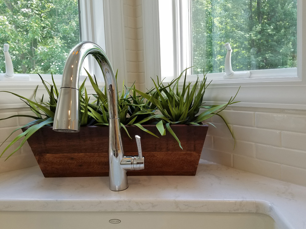 Large transitional u-shaped eat-in kitchen photo with a farmhouse sink, shaker cabinets, white cabinets, quartz countertops, white backsplash, subway tile backsplash, white countertops and an island