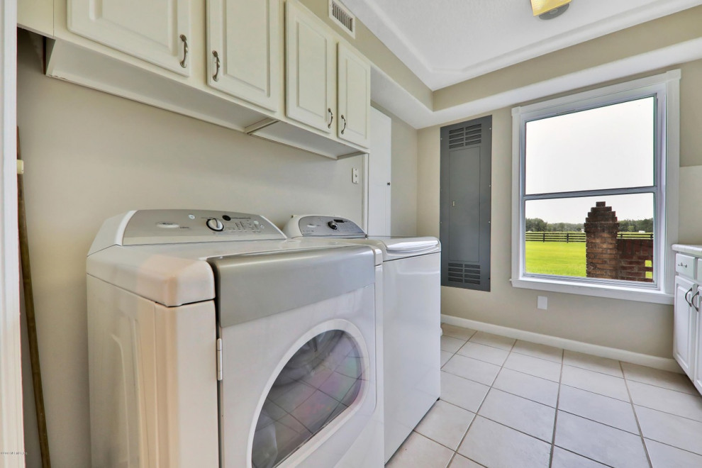 This is an example of a large traditional galley utility room in Jacksonville with raised-panel cabinets, beige cabinets, beige walls, ceramic floors, a side-by-side washer and dryer, multi-coloured floor, white benchtop, a drop-in sink and tile benchtops.
