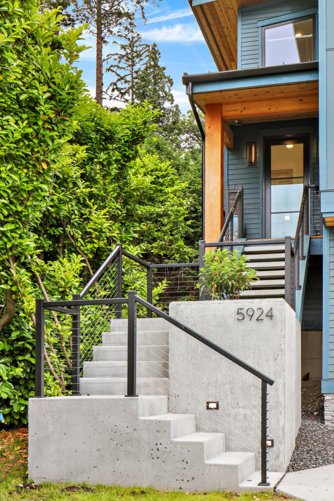 Large beach style three-storey blue house exterior in Seattle with concrete fiberboard siding, a shed roof and a metal roof.