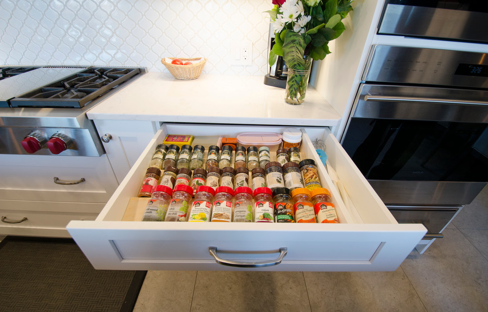 Inspiration for a transitional galley limestone floor eat-in kitchen remodel with an undermount sink, white cabinets, quartz countertops, white backsplash, ceramic backsplash, stainless steel appliances and an island