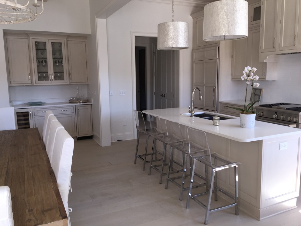 Inspiration for a large transitional l-shaped eat-in kitchen in Miami with an undermount sink, beaded inset cabinets, white cabinets, white splashback, stainless steel appliances and with island.