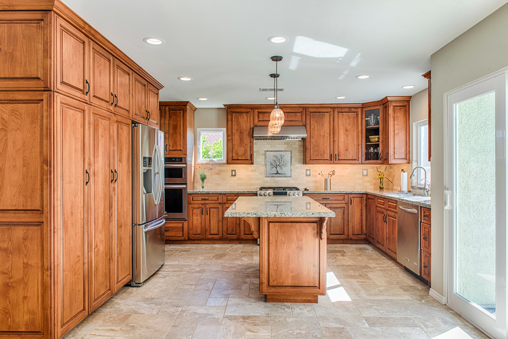 This is an example of a mid-sized traditional kitchen in Los Angeles with medium wood cabinets, granite benchtops, beige splashback, subway tile splashback, stainless steel appliances, porcelain floors and with island.