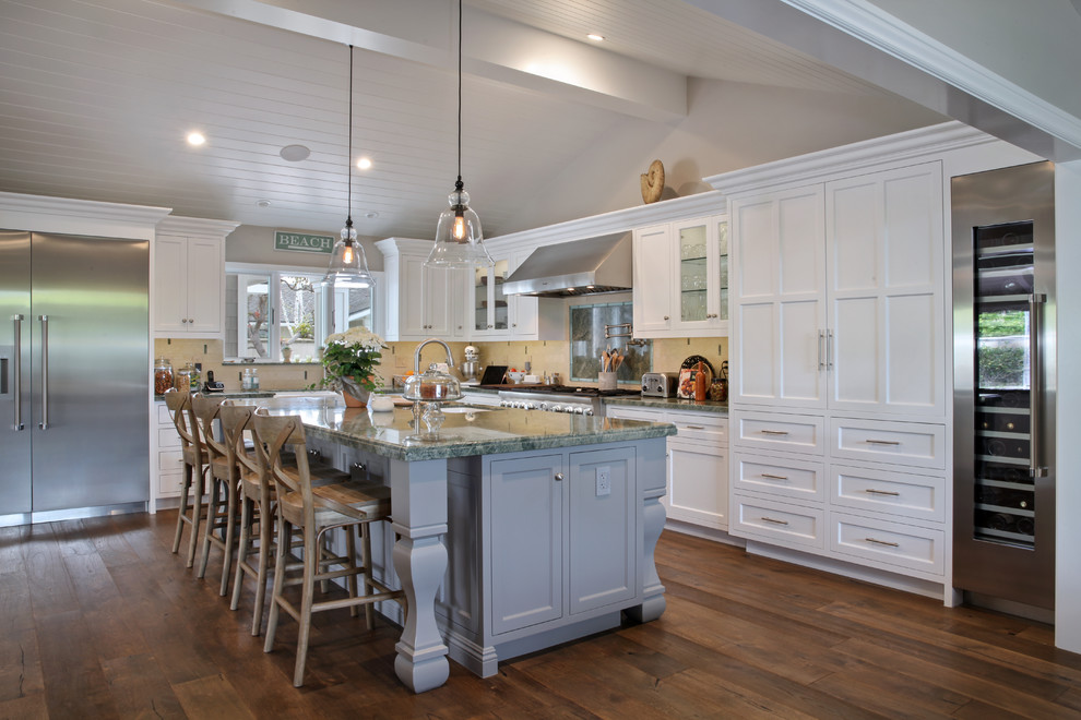 Beach style l-shaped kitchen in Orange County with an undermount sink, shaker cabinets, white cabinets, beige splashback, stainless steel appliances, dark hardwood floors, with island and brown floor.