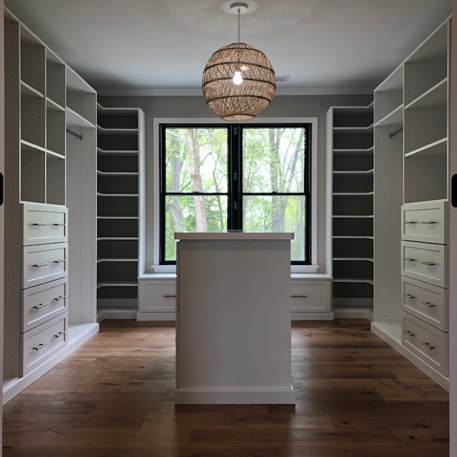 Inspiration for a mid-sized country walk-in wardrobe in Baltimore with shaker cabinets, white cabinets and medium hardwood floors.