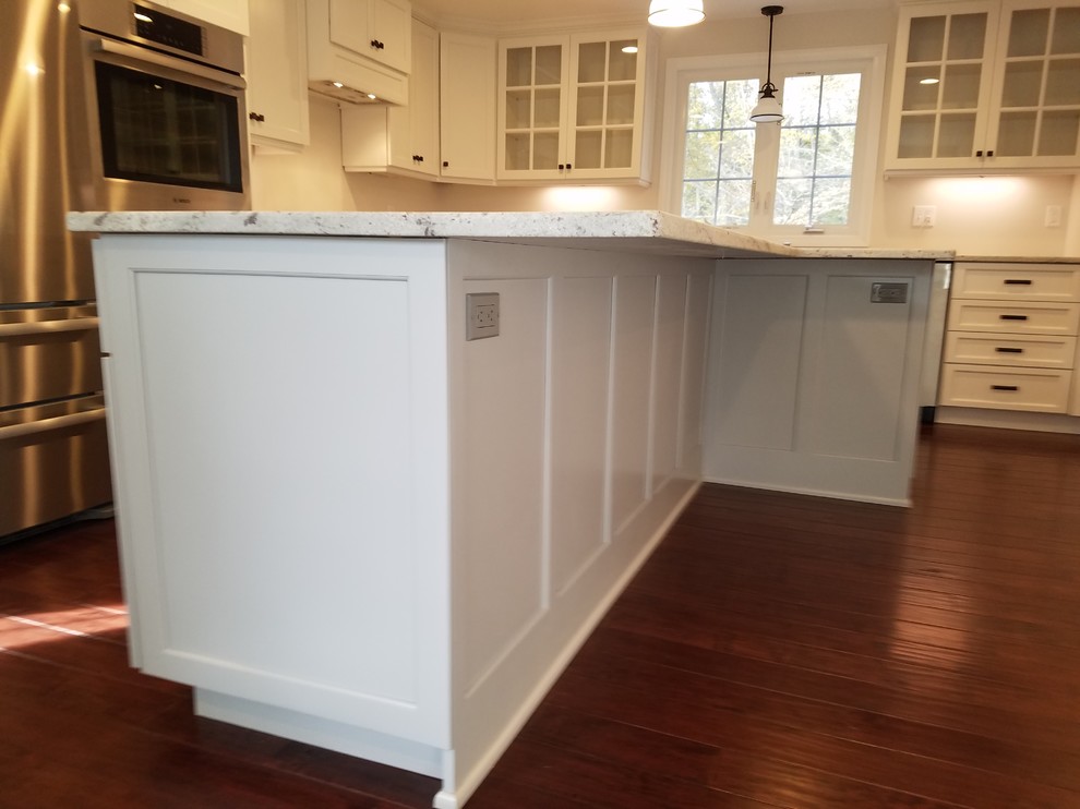 Inspiration for a mid-sized transitional l-shaped dark wood floor and brown floor eat-in kitchen remodel with a farmhouse sink, shaker cabinets, white cabinets, granite countertops, white backsplash, subway tile backsplash, stainless steel appliances and an island