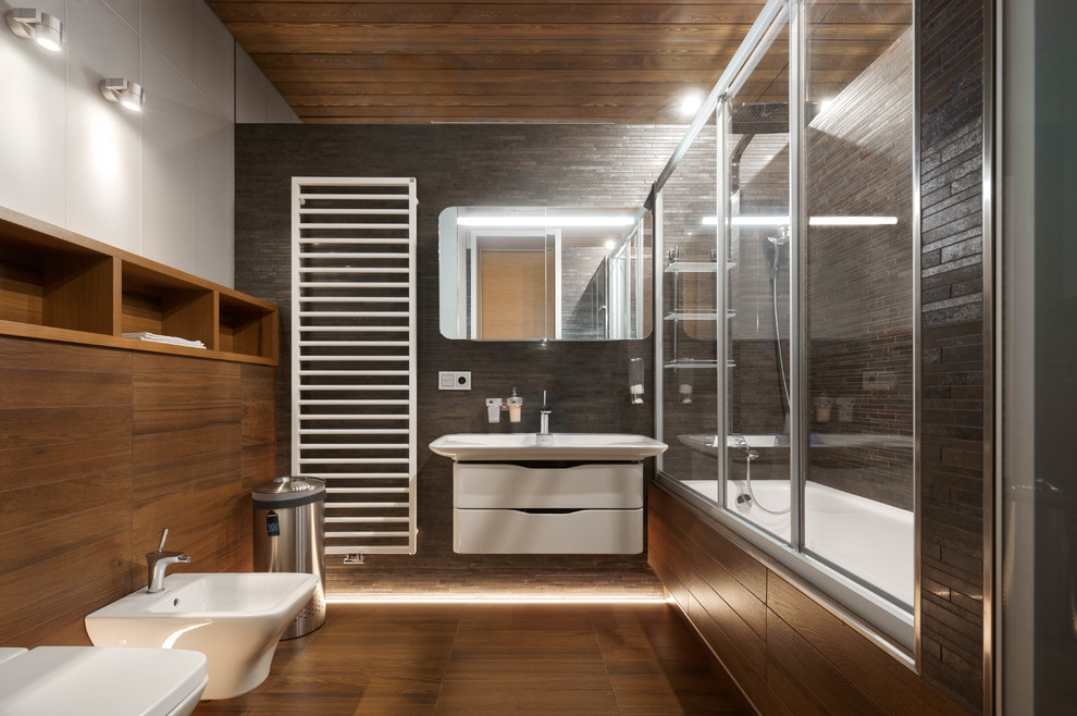 Design ideas for a small contemporary master bathroom in Moscow with marble floors, flat-panel cabinets, white cabinets, an alcove tub, a shower/bathtub combo, a bidet, gray tile, an integrated sink and brown floor.