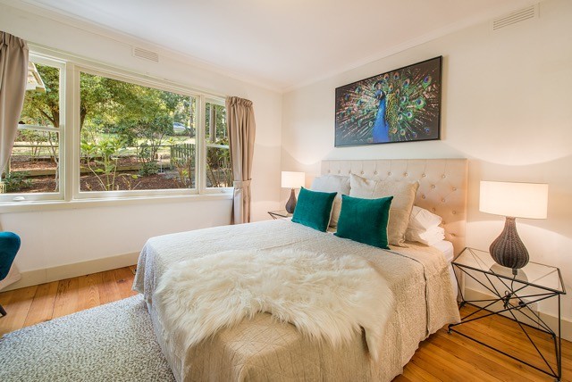 This is an example of a mid-sized country master bedroom in Melbourne with white walls, medium hardwood floors and brown floor.