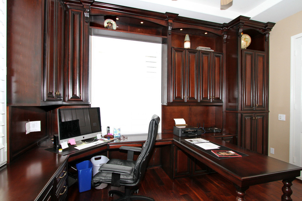 This is an example of a mid-sized traditional study room in Orange County with beige walls, dark hardwood floors, a built-in desk and brown floor.