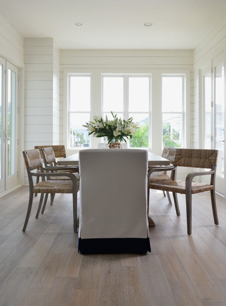 Design ideas for a beach style dining room in Houston with white walls and beige floor.