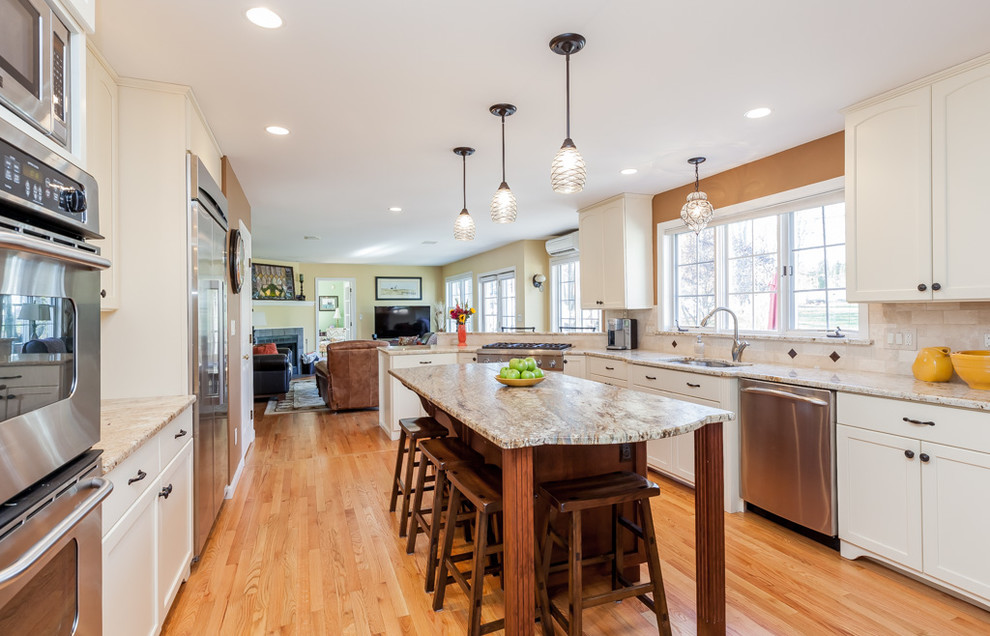 Enclosed kitchen - mid-sized transitional u-shaped light wood floor enclosed kitchen idea in Boston with a double-bowl sink, recessed-panel cabinets, white cabinets, granite countertops, beige backsplash, stone tile backsplash, stainless steel appliances and an island
