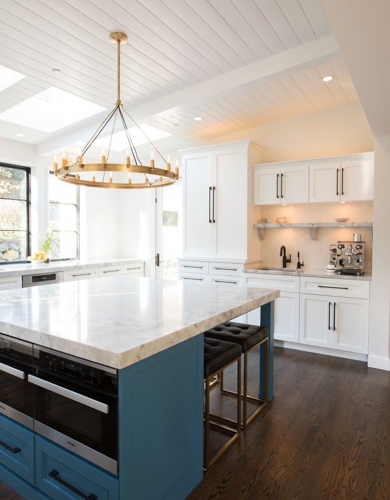 Photo of a large contemporary u-shaped eat-in kitchen in Seattle with recessed-panel cabinets, white cabinets, quartzite benchtops, white splashback, ceramic splashback, stainless steel appliances, medium hardwood floors, with island, brown floor and grey benchtop.
