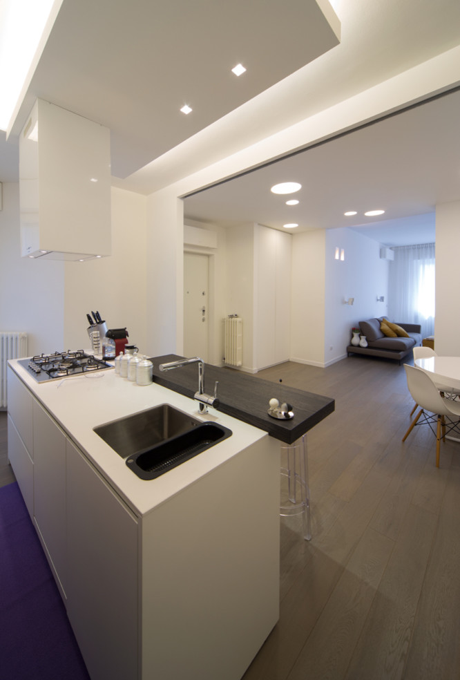 Foto di un cucina con isola centrale minimal con ante lisce e ante bianche