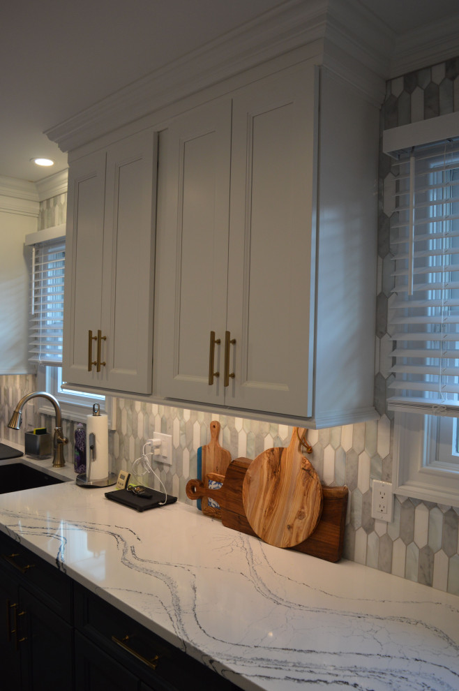 Transitional medium tone wood floor and brown floor kitchen photo in New York with a drop-in sink, marble countertops, white backsplash, ceramic backsplash, stainless steel appliances and white countertops