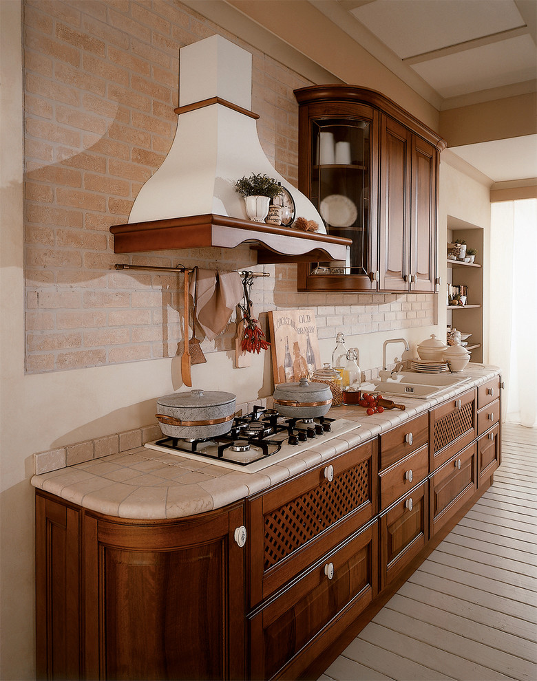 Design ideas for a mid-sized traditional single-wall eat-in kitchen in San Diego with a double-bowl sink, dark wood cabinets, tile benchtops, white splashback, light hardwood floors, no island and raised-panel cabinets.