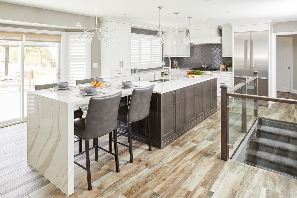 Example of a mid-sized transitional l-shaped light wood floor kitchen design in Toronto with shaker cabinets, gray backsplash, stainless steel appliances, an island, white countertops, a double-bowl sink, white cabinets and marble countertops
