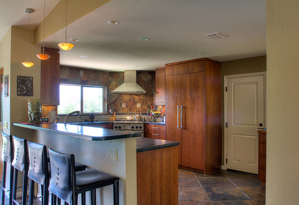 This is an example of a mid-sized asian u-shaped eat-in kitchen in Santa Barbara with a drop-in sink, flat-panel cabinets, brown cabinets, solid surface benchtops, brown splashback, ceramic splashback, stainless steel appliances, ceramic floors, no island and brown floor.