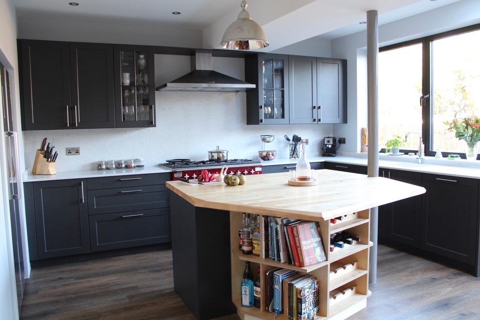 This is an example of a mid-sized eclectic l-shaped open plan kitchen in London with a drop-in sink, shaker cabinets, black cabinets, quartzite benchtops, grey splashback, coloured appliances, vinyl floors, with island and brown floor.
