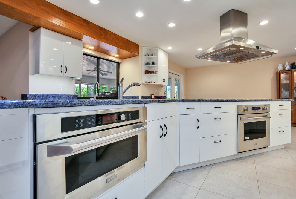 Photo of a mid-sized contemporary galley eat-in kitchen in Tampa with flat-panel cabinets, white cabinets, blue splashback, stainless steel appliances, with island and blue benchtop.