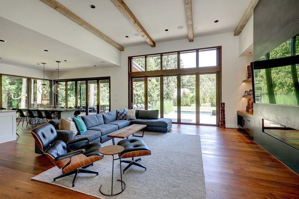 This is an example of a large contemporary open concept living room in Portland with a home bar, white walls, medium hardwood floors, a ribbon fireplace, a concrete fireplace surround and a wall-mounted tv.