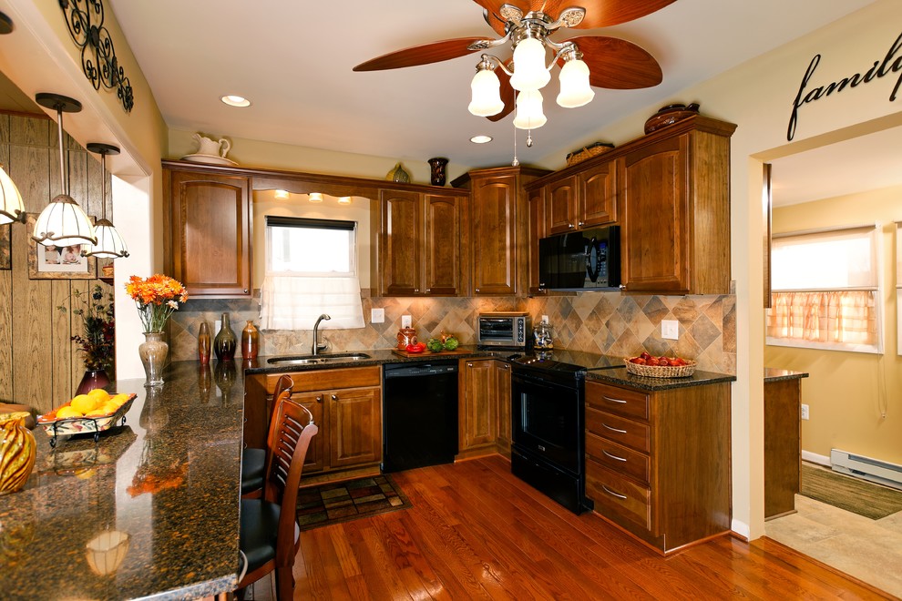 Transitional l-shaped eat-in kitchen photo in DC Metro with a double-bowl sink, furniture-like cabinets, medium tone wood cabinets, granite countertops, beige backsplash, mosaic tile backsplash and black appliances