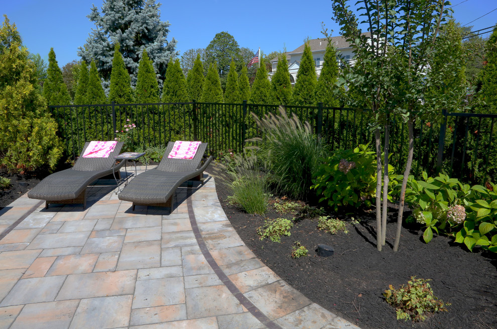 Photo of a mid-sized traditional backyard patio in New York with a water feature, concrete pavers and no cover.