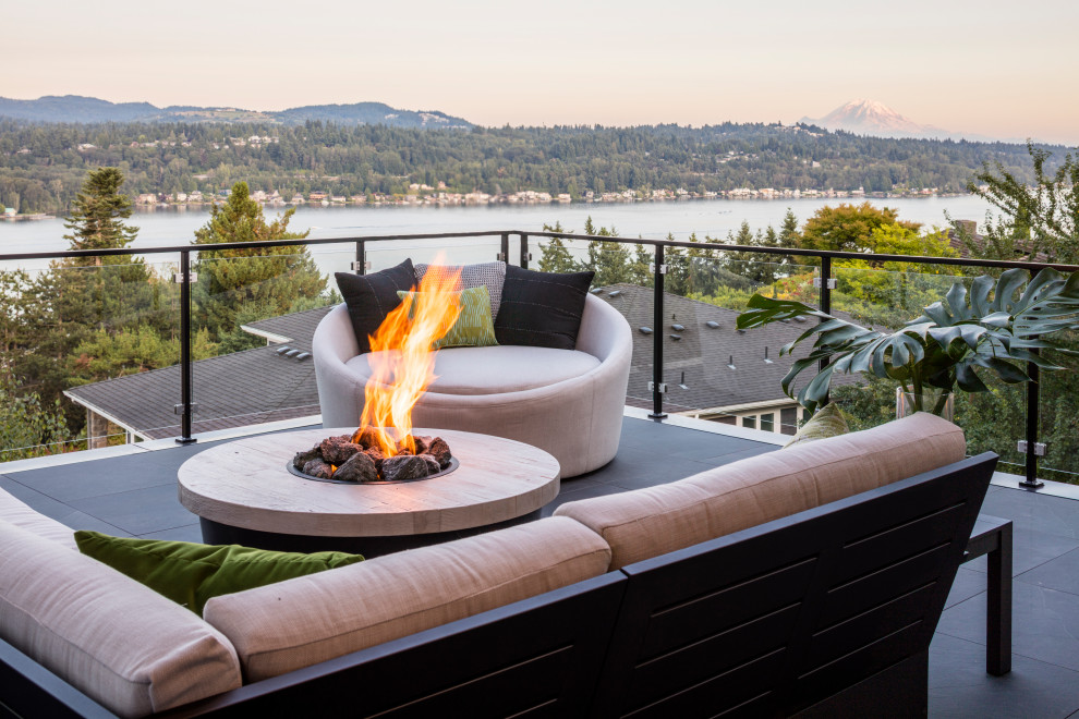 This is an example of a mid-sized modern side yard patio in Seattle with a fire feature, tile and a roof extension.