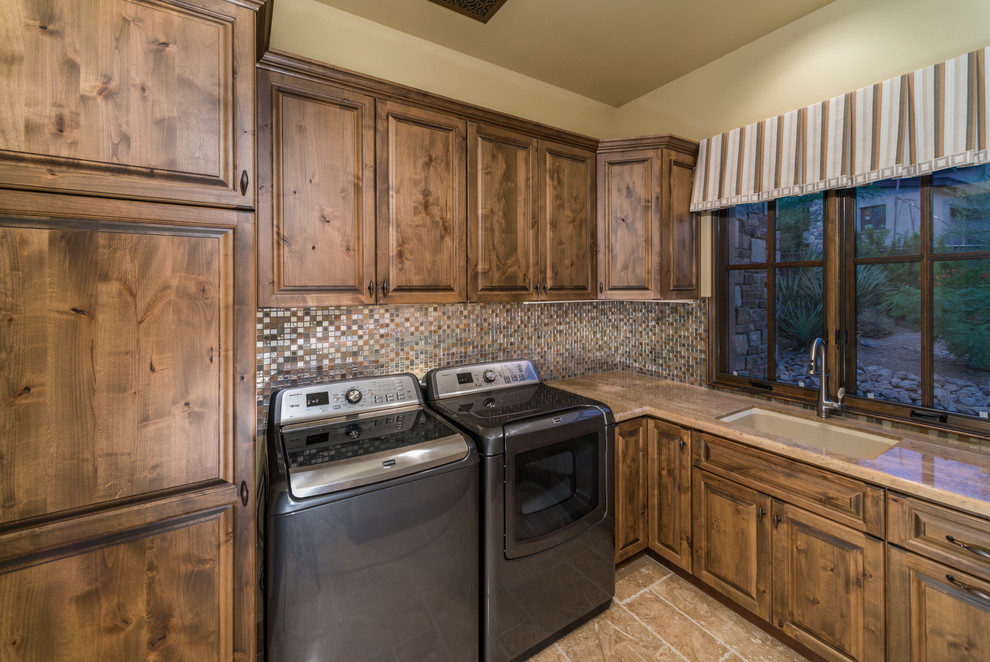 Design ideas for an expansive traditional u-shaped dedicated laundry room in Phoenix with a drop-in sink, raised-panel cabinets, medium wood cabinets, wood benchtops, beige walls, travertine floors and a side-by-side washer and dryer.