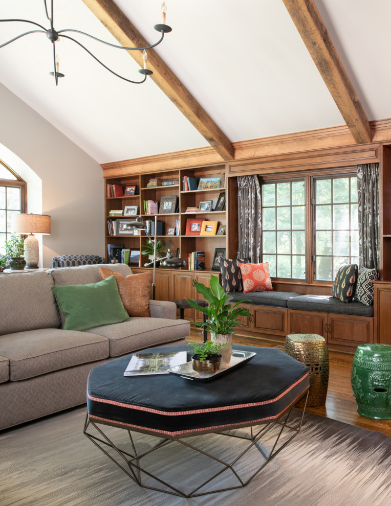 Foto di un soggiorno boho chic con libreria, pareti grigie, pavimento in legno massello medio e travi a vista