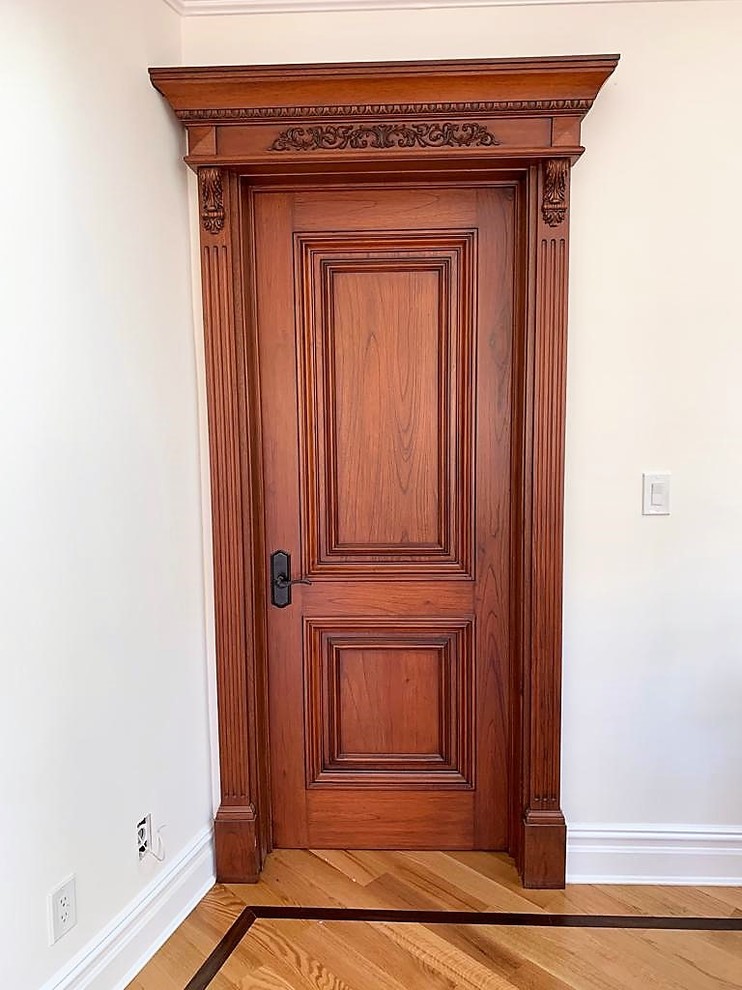 This is an example of a small vestibule in New York with white walls, laminate floors, a single front door, a medium wood front door and green floor.