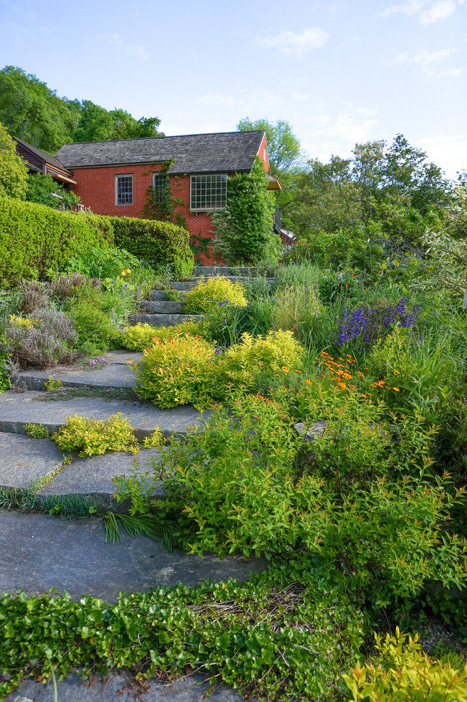 This is an example of a country backyard full sun garden in New York with natural stone pavers.