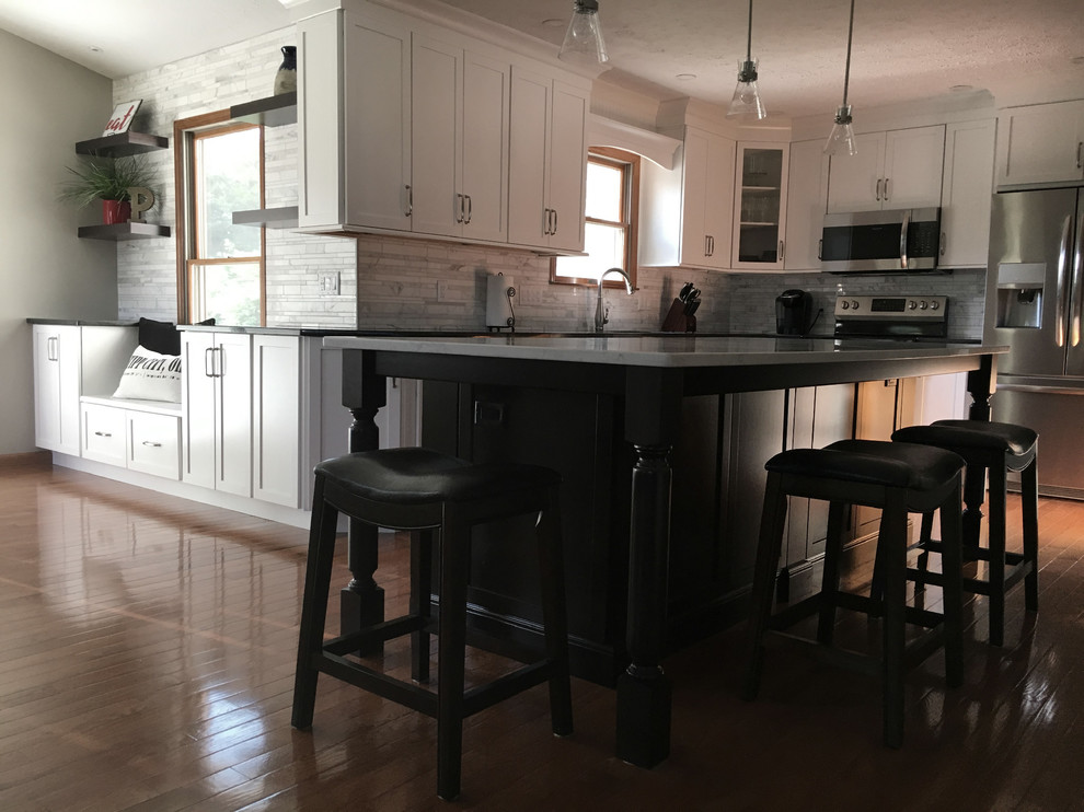 Large transitional single-wall medium tone wood floor eat-in kitchen photo with an undermount sink, shaker cabinets, white cabinets, granite countertops, multicolored backsplash, marble backsplash, stainless steel appliances, an island and black countertops
