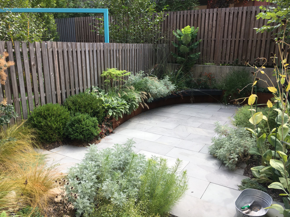 Diseño de patio moderno de tamaño medio en patio trasero con jardín de macetas y adoquines de piedra natural