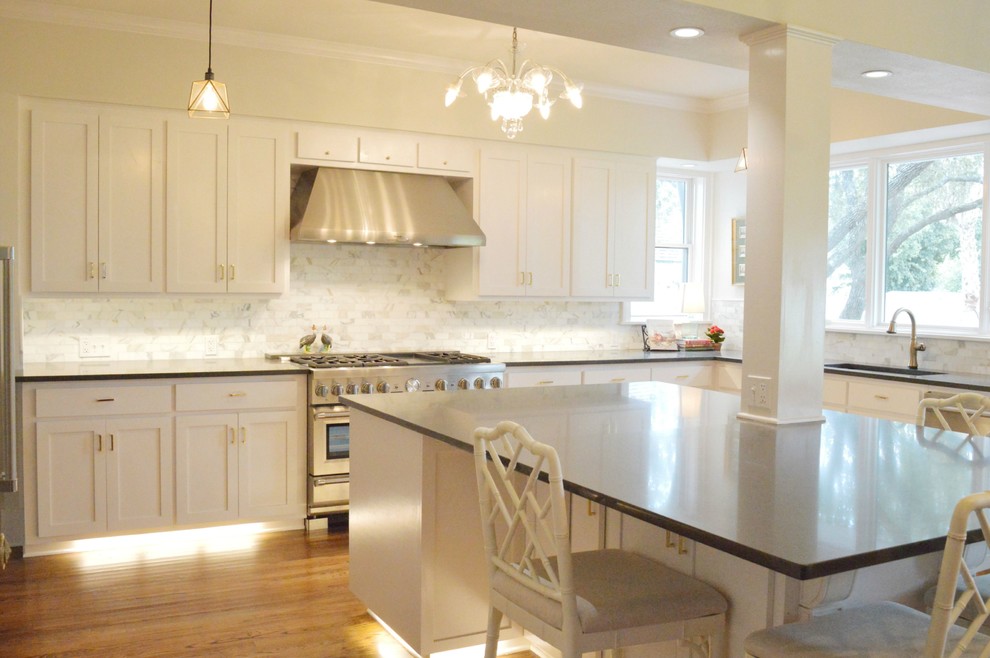 Kitchen photo in Austin with an undermount sink, shaker cabinets, white cabinets, quartz countertops, white backsplash, stone tile backsplash, stainless steel appliances and an island