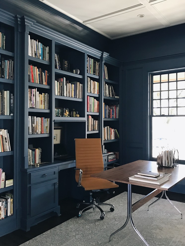 This is an example of a transitional home office in Other with a library, blue walls and a freestanding desk.
