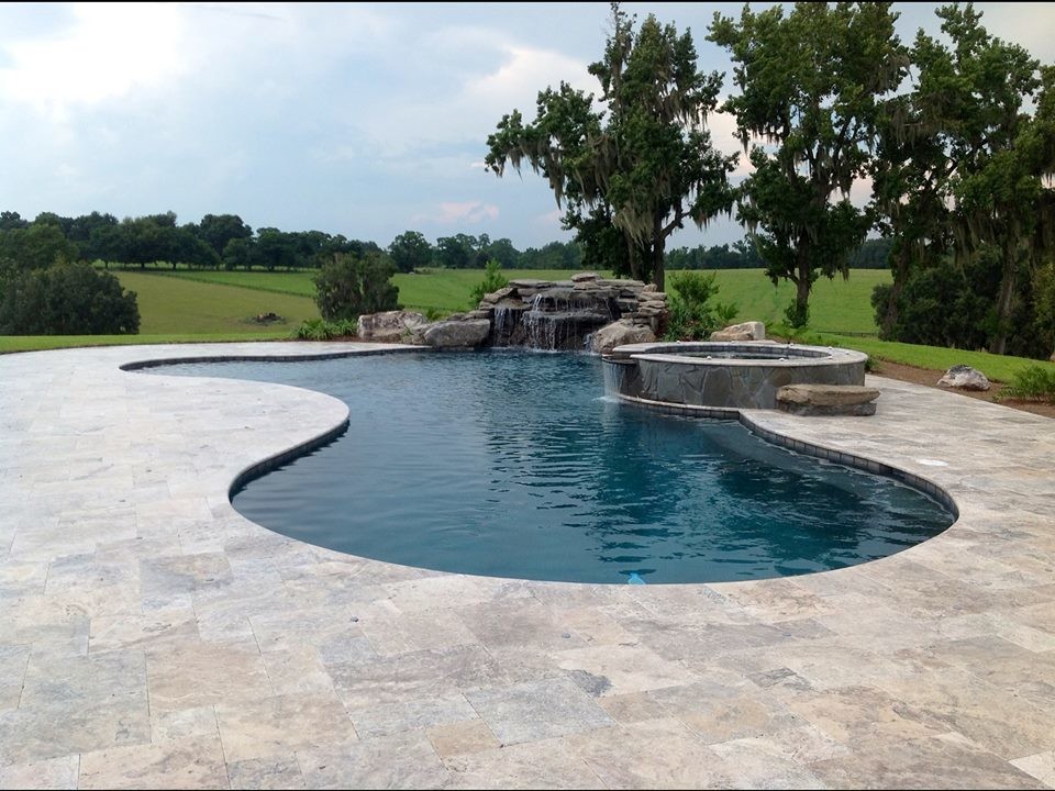 Inspiration for a large tropical backyard kidney-shaped lap pool in Other with natural stone pavers.