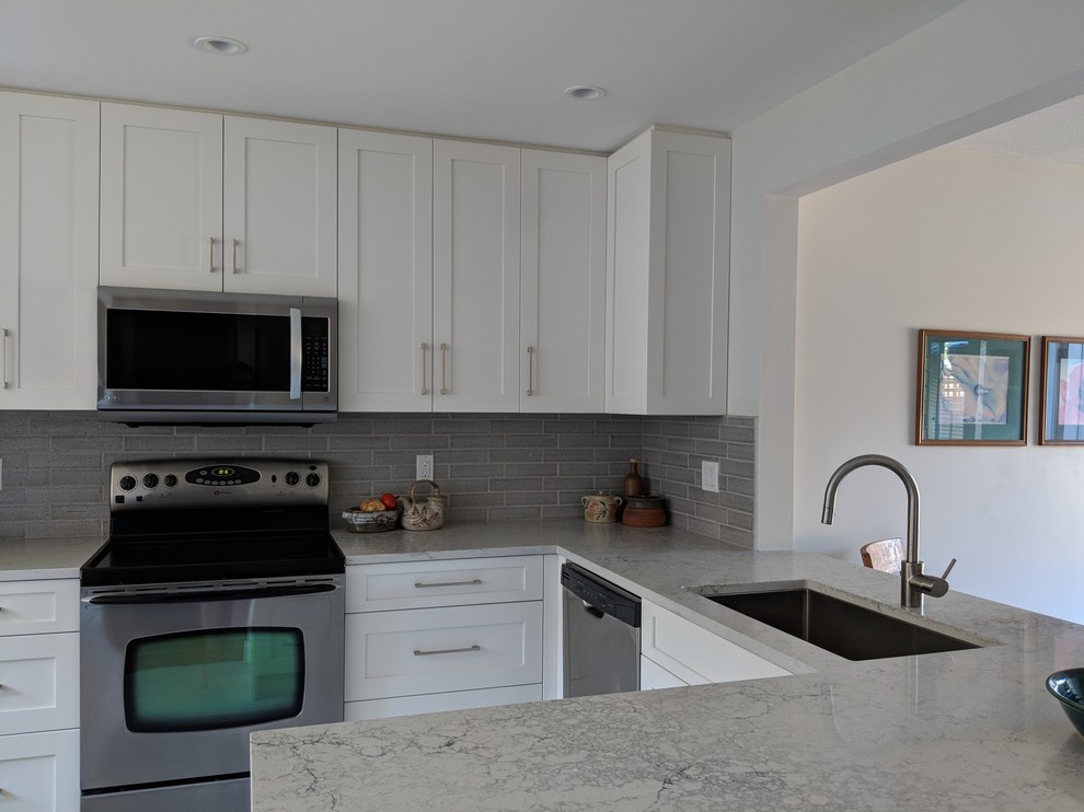 This is an example of a small transitional u-shaped eat-in kitchen in Vancouver with a single-bowl sink, shaker cabinets, white cabinets, quartz benchtops, grey splashback, ceramic splashback, stainless steel appliances, vinyl floors, no island, beige floor and grey benchtop.