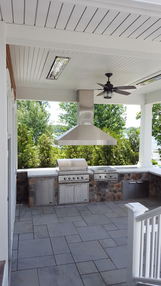 This is an example of a large arts and crafts backyard patio in Other with an outdoor kitchen, tile and a roof extension.