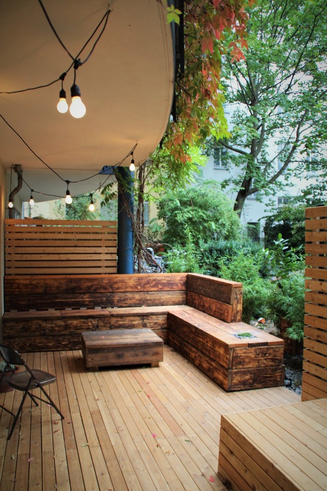 This is an example of a small traditional backyard deck in Berlin with a roof extension.