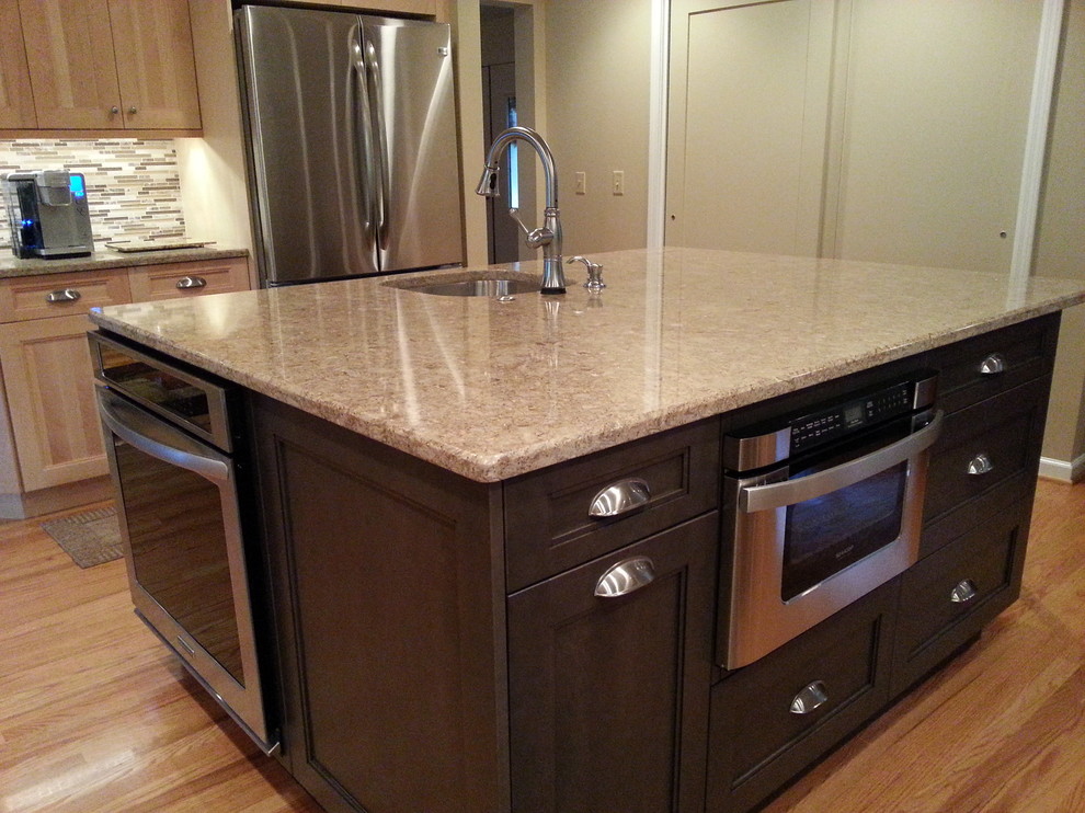 Inspiration for a mid-sized transitional l-shaped medium tone wood floor kitchen pantry remodel in New York with an undermount sink, raised-panel cabinets, light wood cabinets, beige backsplash, stone slab backsplash, stainless steel appliances and an island