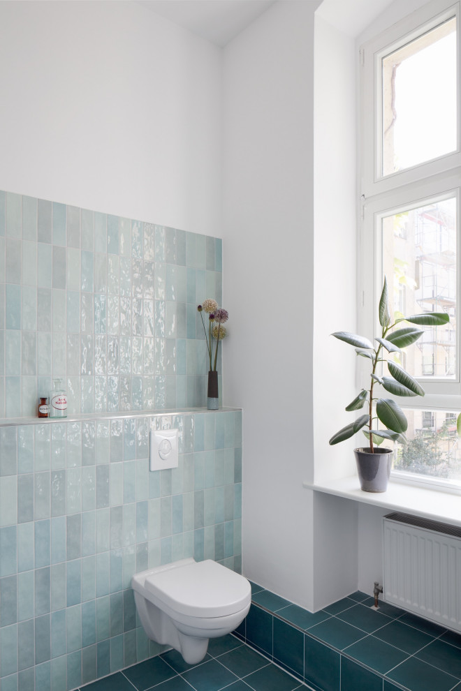Photo of a medium sized contemporary shower room bathroom in Berlin with a shower/bath combination, a two-piece toilet, blue tiles, ceramic tiles, blue walls, cement flooring, a wall-mounted sink, blue floors, an open shower, an enclosed toilet, a single sink and a floating vanity unit.