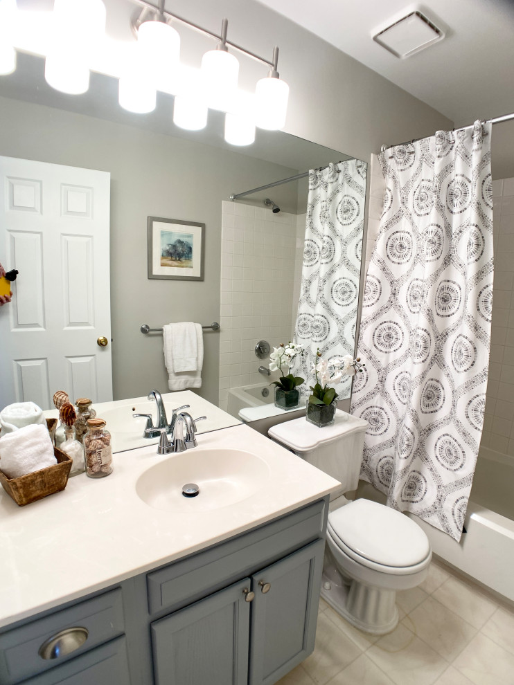 This is an example of a small kids bathroom in DC Metro with shaker cabinets, grey cabinets, an alcove tub, a shower/bathtub combo, a two-piece toilet, grey walls, ceramic floors, an integrated sink, engineered quartz benchtops, beige floor, a shower curtain, white benchtops, a single vanity and a built-in vanity.