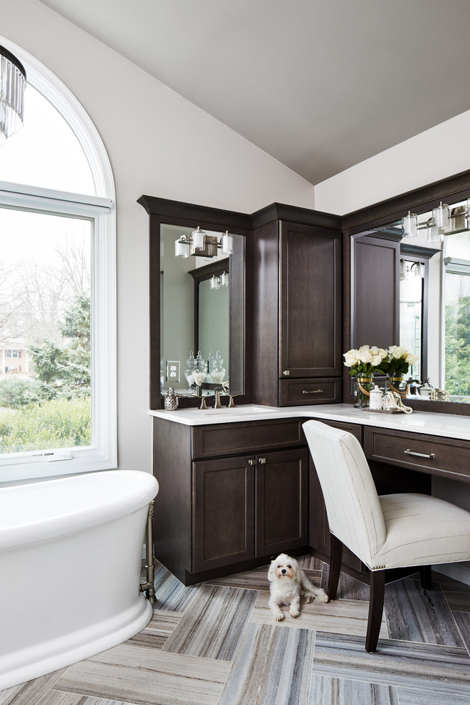 Photo of a mid-sized transitional master bathroom in Chicago with shaker cabinets, dark wood cabinets, a freestanding tub, a corner shower, a two-piece toilet, beige tile, porcelain tile, beige walls, marble floors, an undermount sink, engineered quartz benchtops, multi-coloured floor, a hinged shower door and white benchtops.
