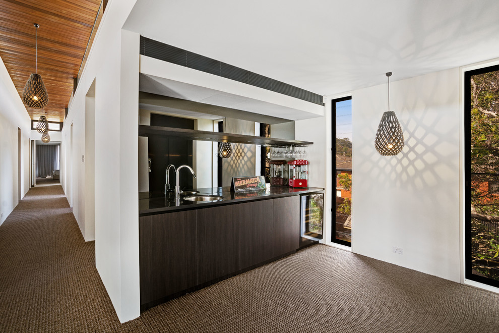 Small contemporary home bar in Central Coast with an undermount sink, flat-panel cabinets, dark wood cabinets, solid surface benchtops, black splashback, mirror splashback, carpet and black benchtop.