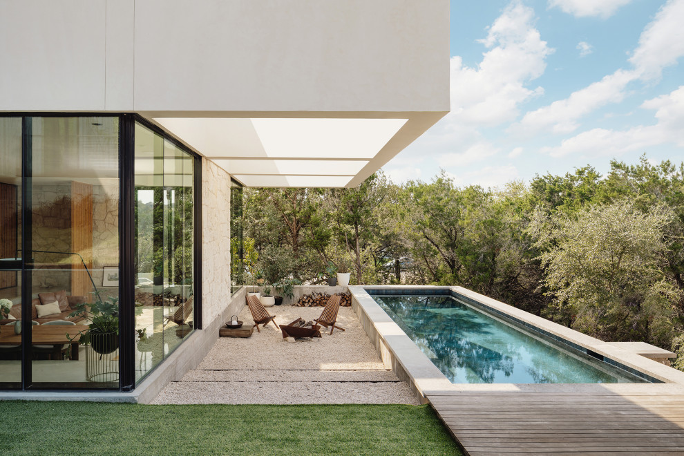 Imagen de piscina moderna rectangular en patio trasero con granito descompuesto